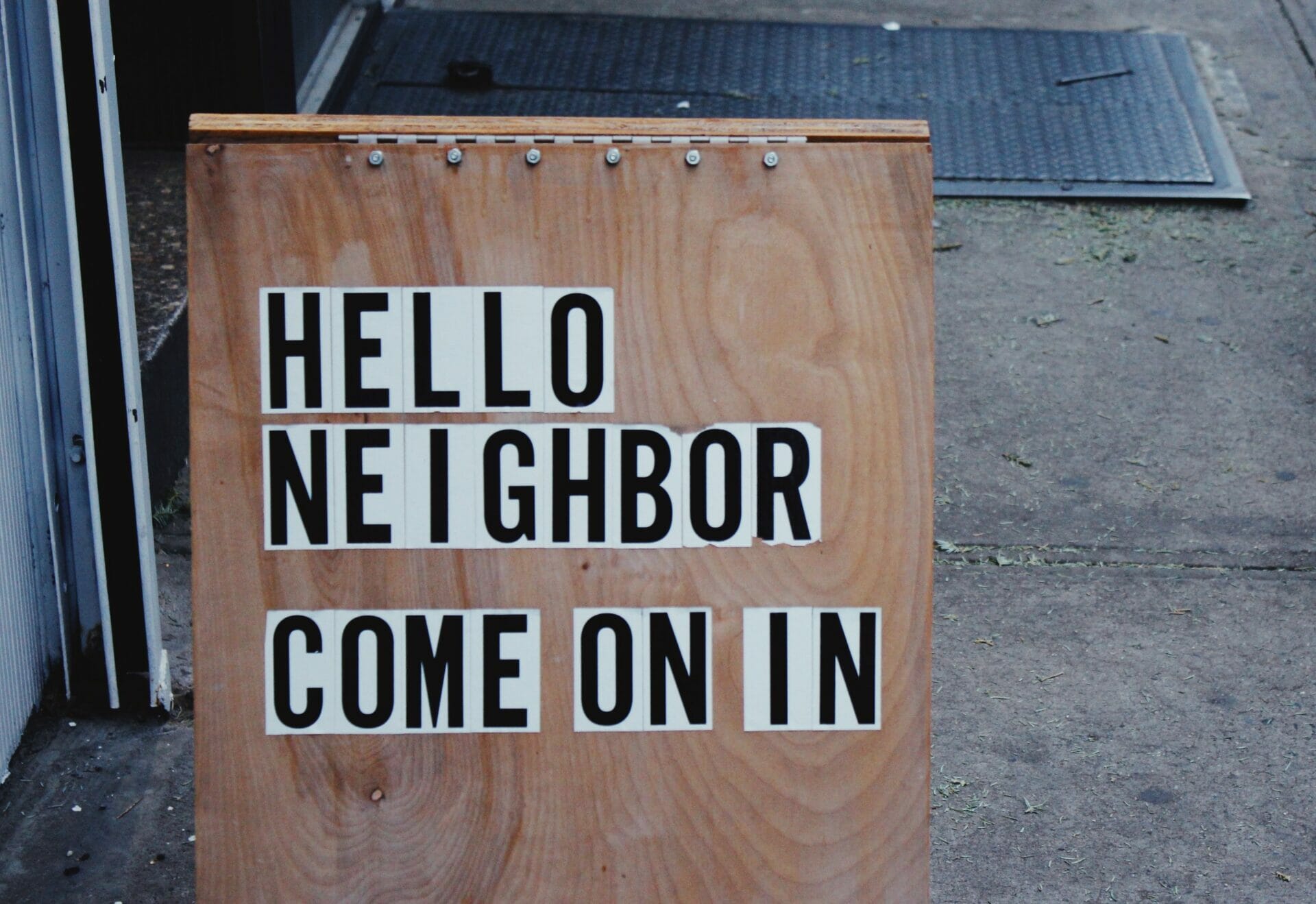 Houten bord met daarop de tekst 'Hello neighbor come on in' (vertaling: Halle buurtjes, kom maar binnen)