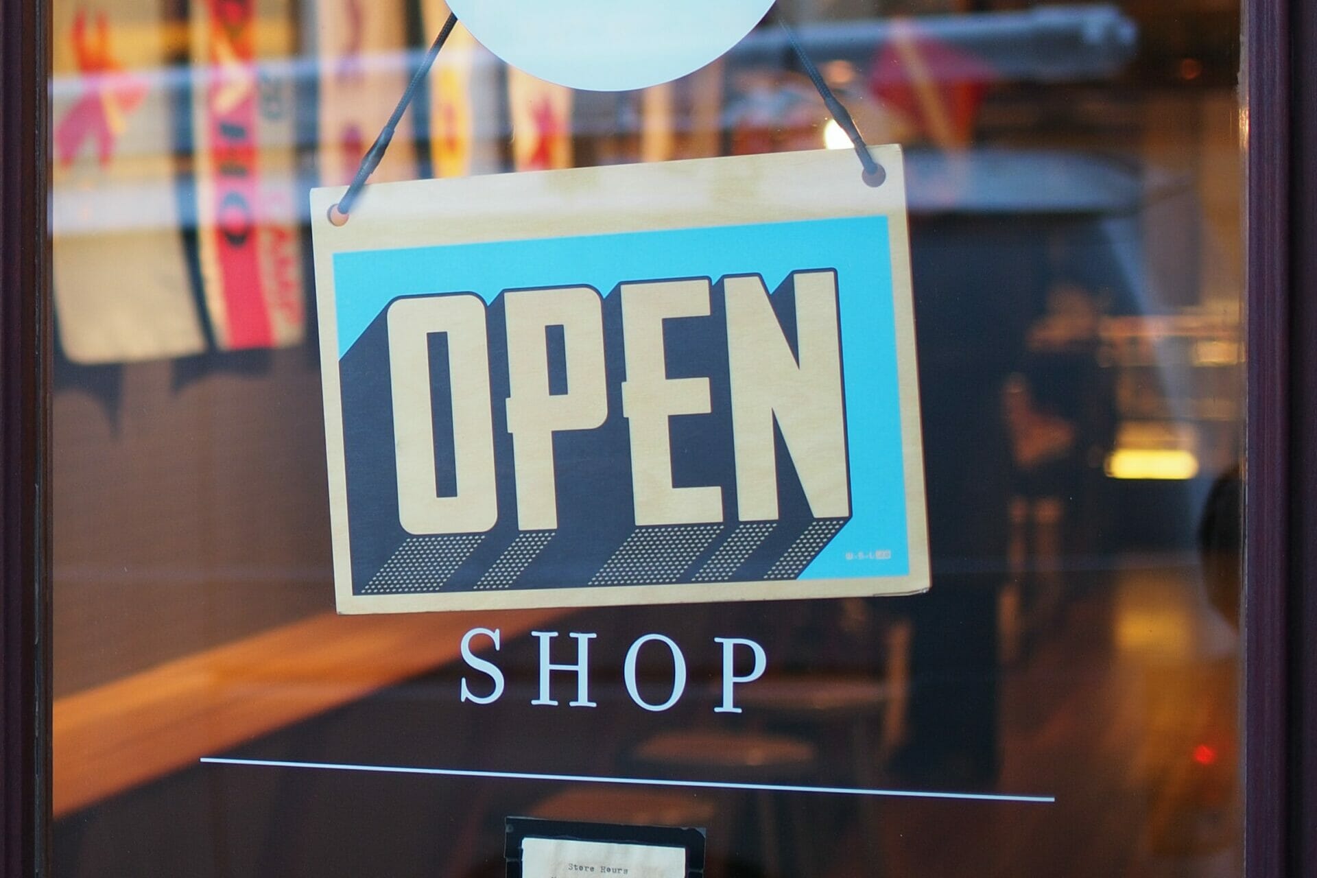 Een winkeldeur met daarop een bord met de tekst "open".